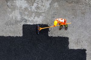 Mothetho Civils worker spreading fresh hot-mix asphalt