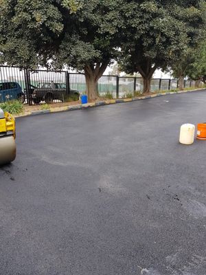 Freshly tarred surface at a Gauteng job site, roller edge visible, palisade boundary in background